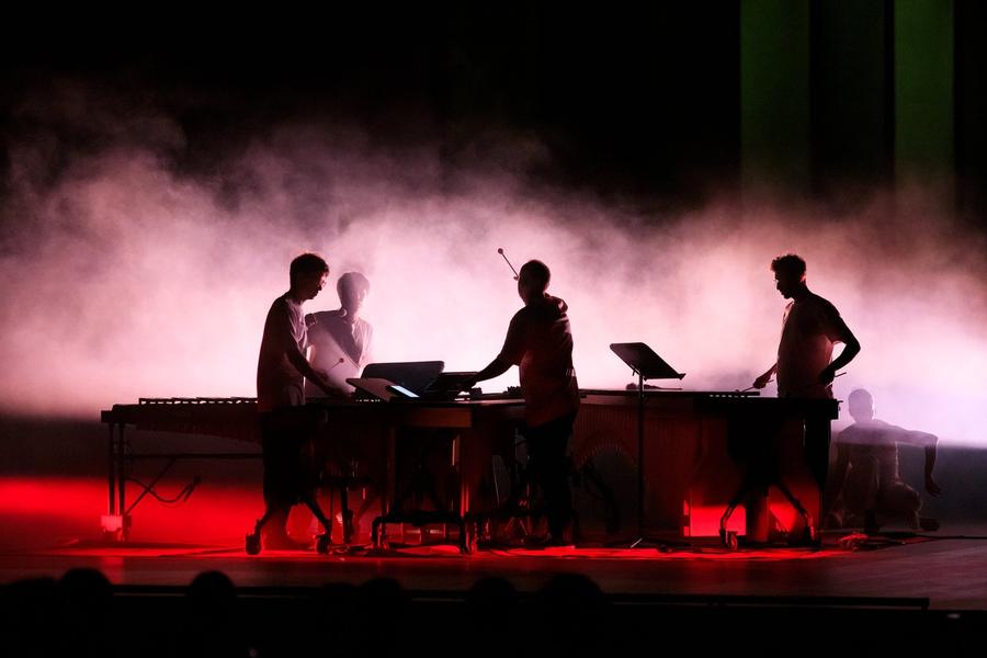 Percussionisti in controluce alle marimbe, nel fumo rosso