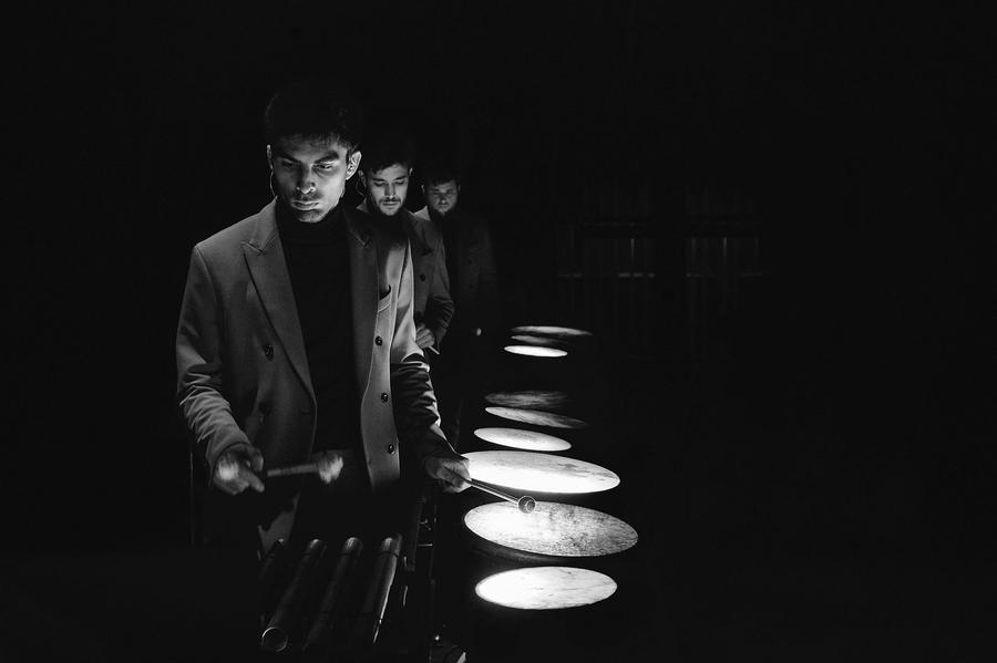 Percussionista tra piatti illuminati, in bianco e nero